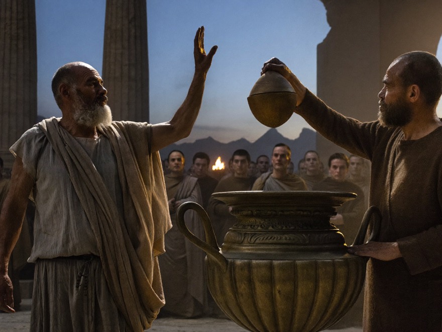 A bearded philosopher debates before gathered citizens in the agora at dusk while a ballot is dropped into a great bronze voting urn